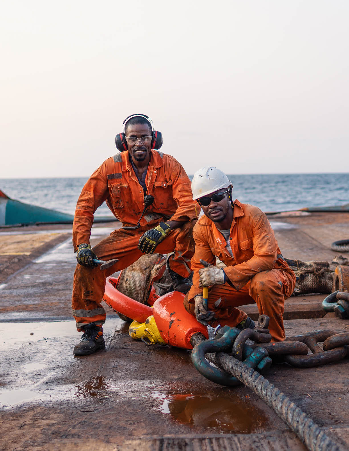Seamen AB or Bosun on deck of offshore vessel or ship , wearing PPE personal protective equipment - helmet, coverall, lifejacket, goggles. They prepare towing wire