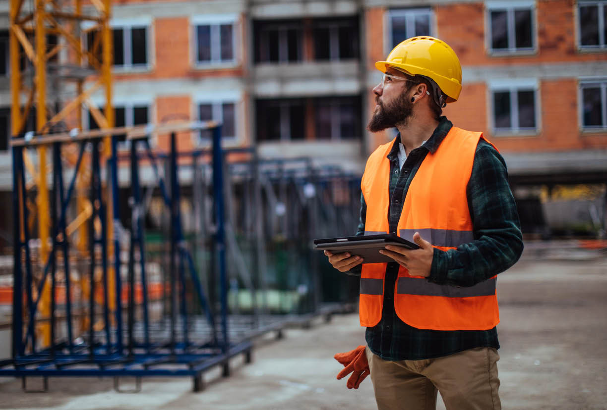 Young construction worker using his digital tablet while at a building site